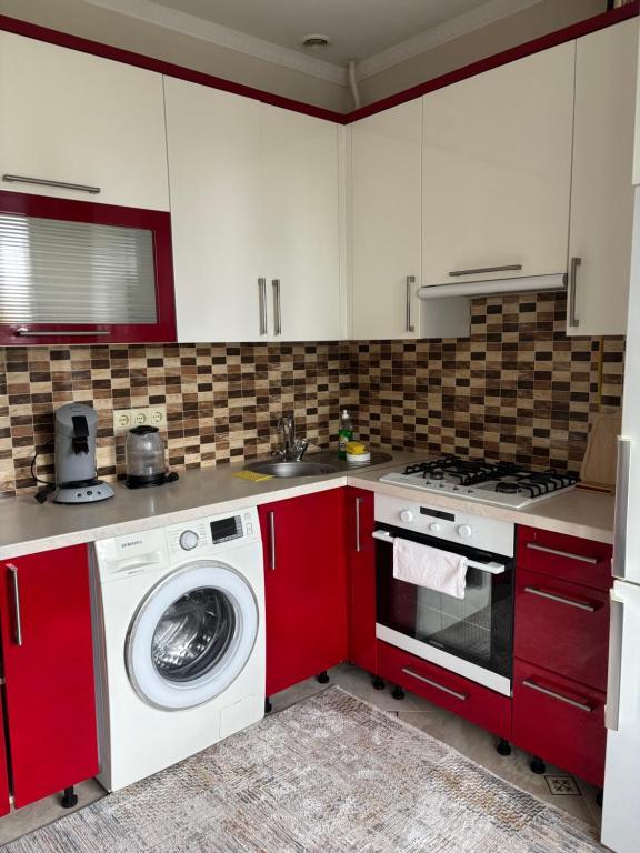 eine Küche mit roten Schränken und einer Waschmaschine in der Unterkunft Apartament chirie la zi in Chişinău