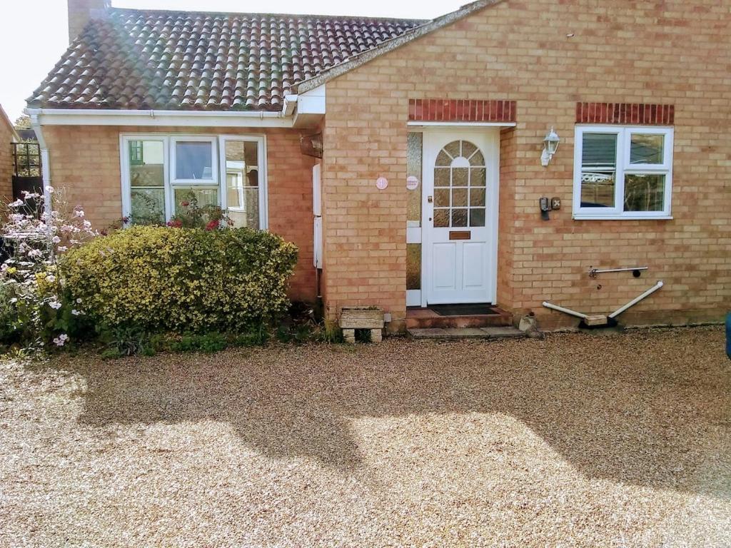 a brick house with a white door and a yard at Bungalow in Cambridge- 3 bedrooms in CBG