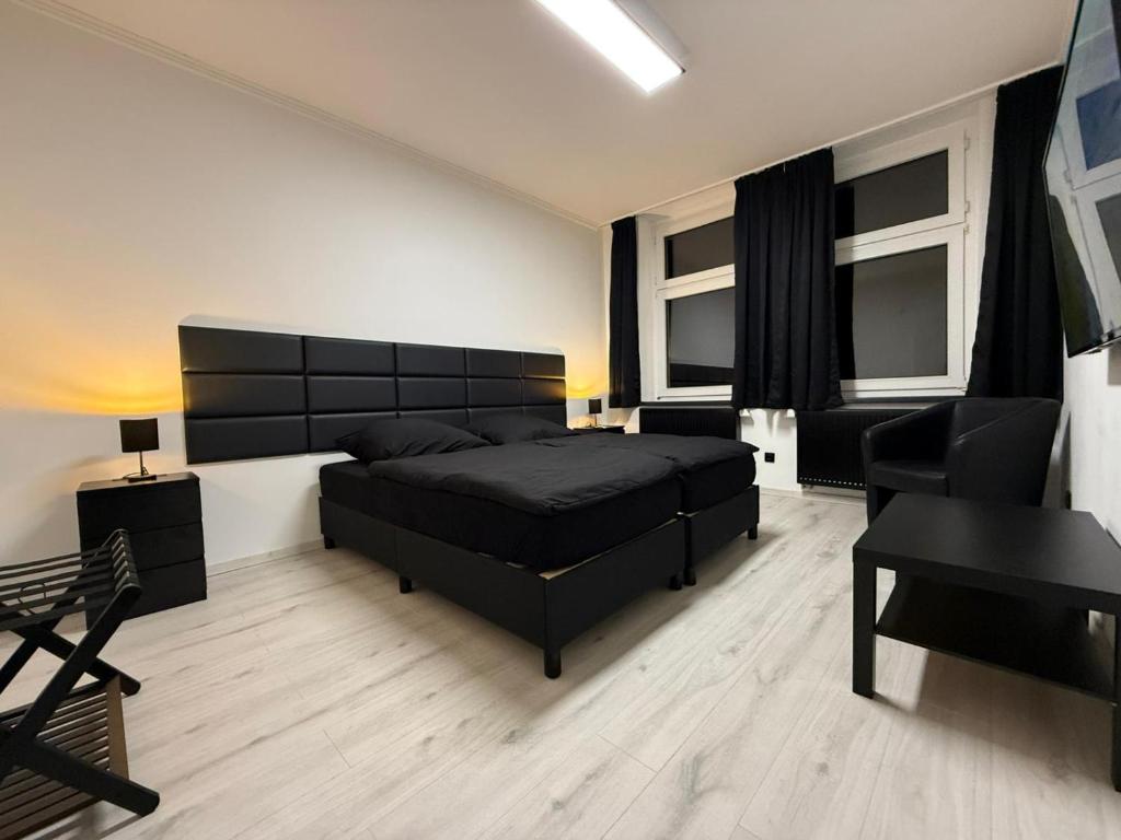 Schlafzimmer mit einem schwarzen Bett und einem Schreibtisch in der Unterkunft Freshly renovated City Apartments Essen KITCHEN WIFI near Düsseldorf Airport in Essen