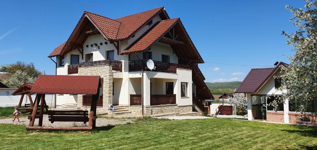 una casa grande con techo rojo en un patio en Zestrea Bunicilor, en Bodeşti
