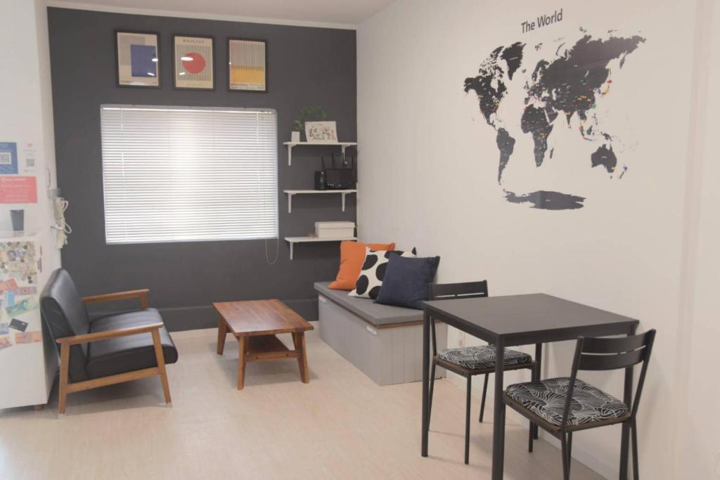a room with a table and chairs and a world map on the wall at Transit Hostel in Izumi-Sano