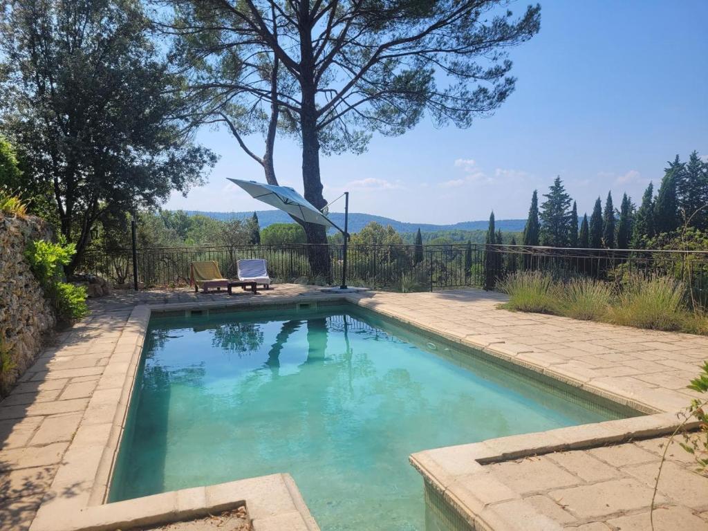 une piscine avec un banc et un arbre dans l'établissement La chouette paisible, à Villecroze