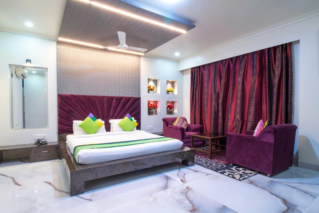a bedroom with a bed and two purple chairs at Hotel Rockland & Restaurant in Jaipur