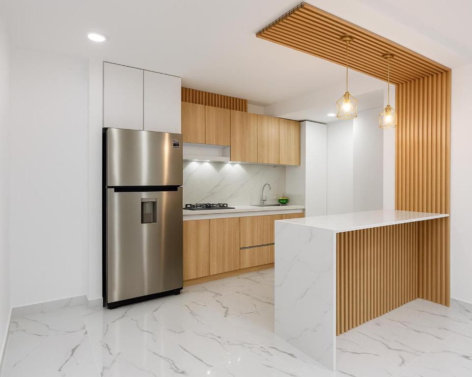 Una cocina con refrigerador de acero inoxidable y gabinetes de madera. en APARTAMENTO FAMIliar MELGAR, en Melgar