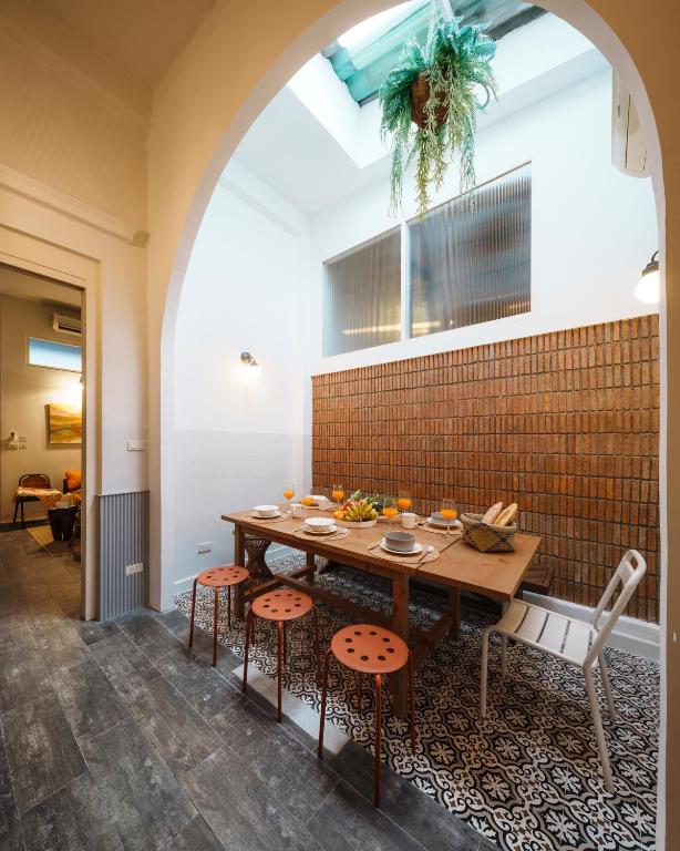 a dining room with a table and stools at Non Inn Entire Historic 5 Bedroom Riverside Shophouse near ICONSIAM for Families and Groups in Bang Rak