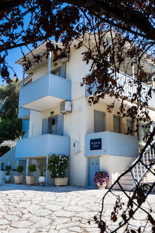 a white building with blue balconies and plants at Pansion Margarita in Agios Nikitas