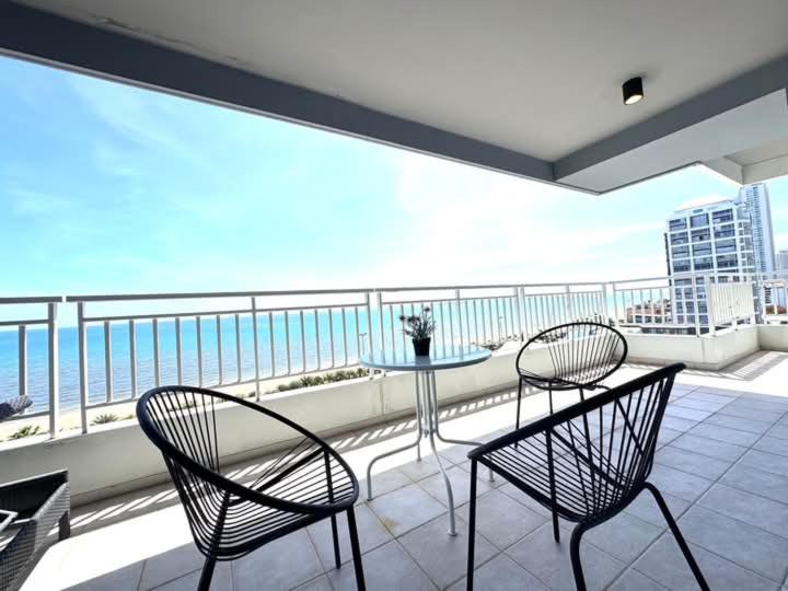 Dos sillas y una mesa en un balcón con vista al mar. en Premium 3bedroom120sqm 15floor วิวทะเล frontbeach seaview, en Jomtien Beach