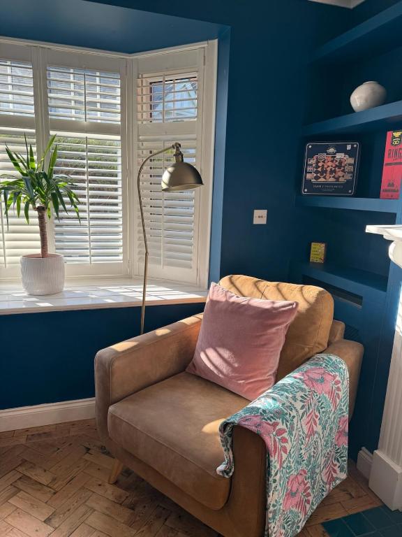 ein Wohnzimmer mit einer Couch und einem Fenster in der Unterkunft Life's A Beach - cosy, luxury cottage in Ashley Cross, Poole in Parkstone