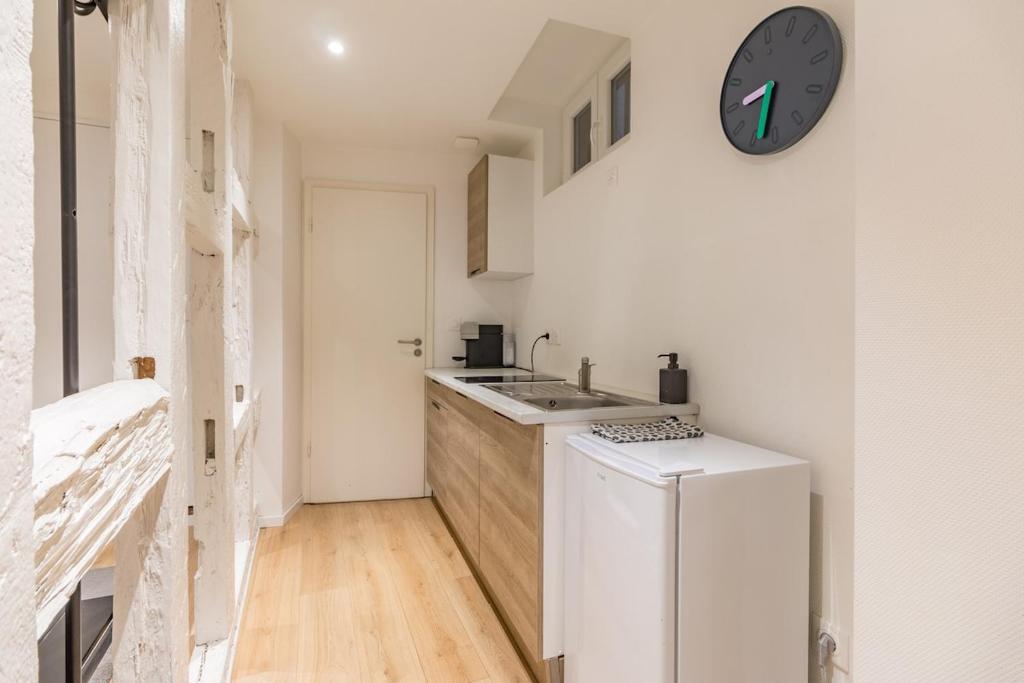 een keuken met een wastafel en een klok aan de muur bij Hyper Centre Studio Strasbourg Cathedral in Straatsburg