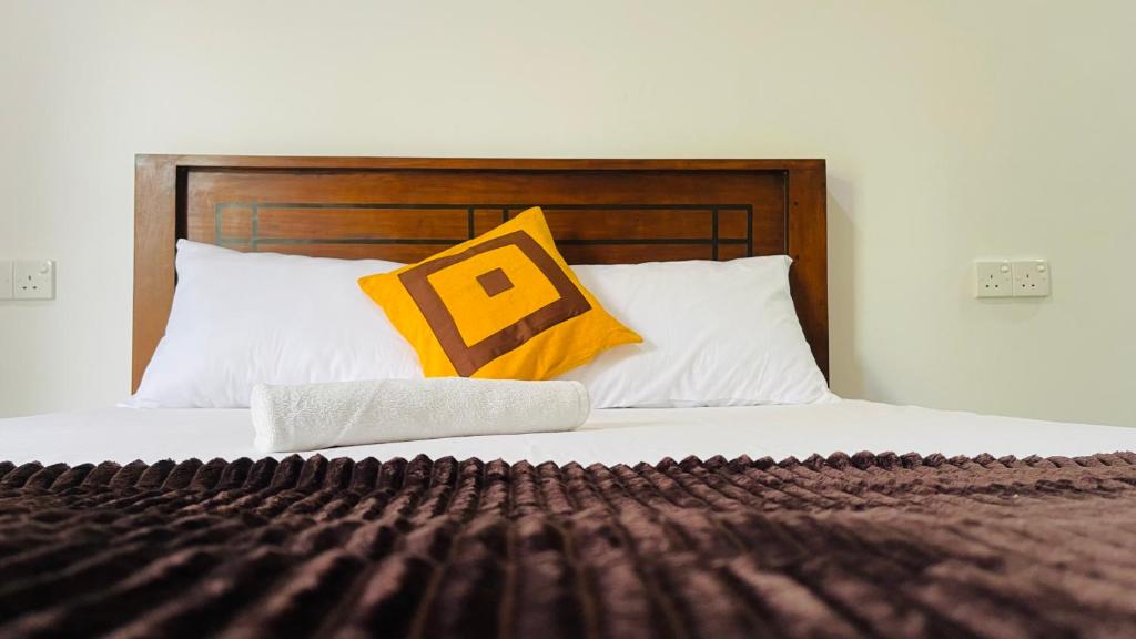 ディックウェラにあるThe Sandora Villaのベッド1台(木製のヘッドボード、黄色い枕付)