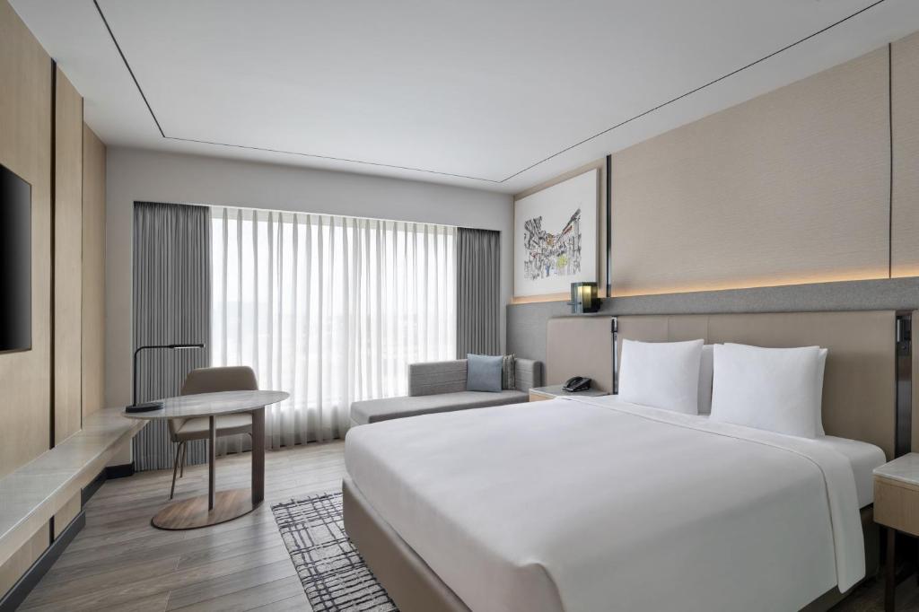 a hotel room with a large white bed and a desk at Courtyard by Marriott Mumbai International Airport in Mumbai