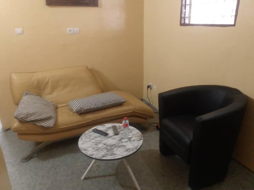 un salon avec un canapé et une chaise dans l'établissement Séjour Plus Bénin, à Cotonou Cadjehoun