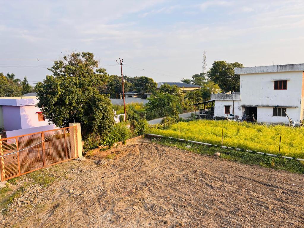 a dirt road with a fence and a house at Jim Corbett Guest House in Jhirna