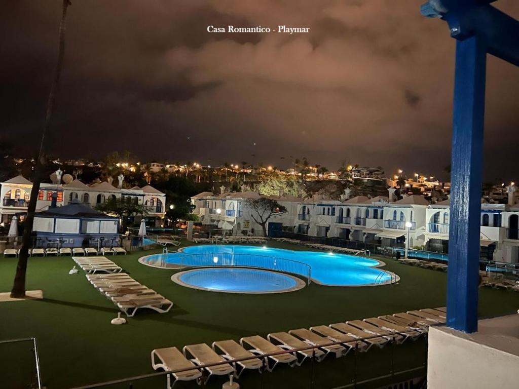 a swimming pool at night with chairs and houses at Casa Romantico - Playmar - Maspalomas in Maspalomas