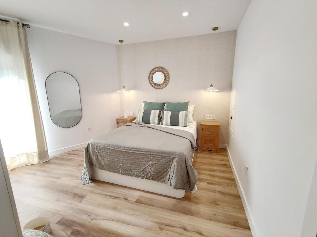 biała sypialnia z łóżkiem i lustrem w obiekcie Apartamento-loft - Rincón de Belén w mieście Jaén