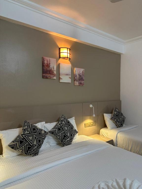 a hotel room with two beds and a light on the wall at The G Ten Holiday Inn in Hulhumale