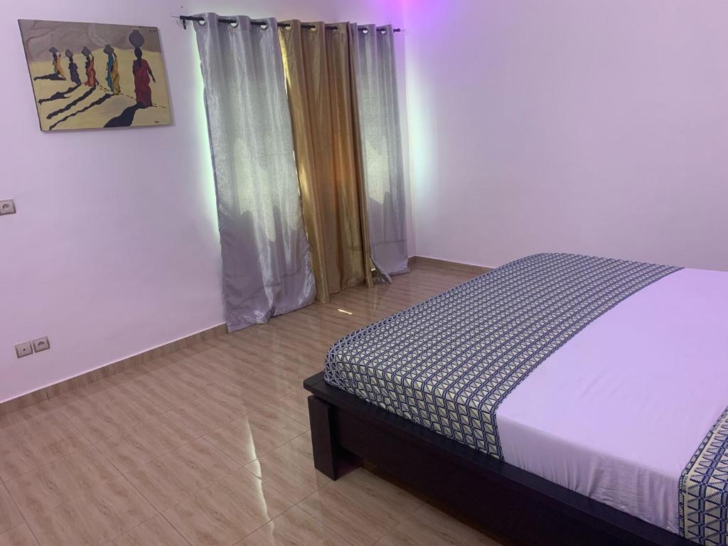 a bedroom with a bed and a window with curtains at Appart Séjour plus Bénin in Cotonou