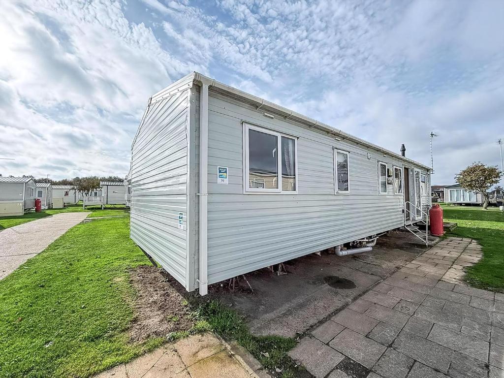 a mobile home is parked in a yard at Great Caravan With Central Lounge & Wifi At Broadland Sands, Suffolk Ref 20070Bs in Hopton on Sea