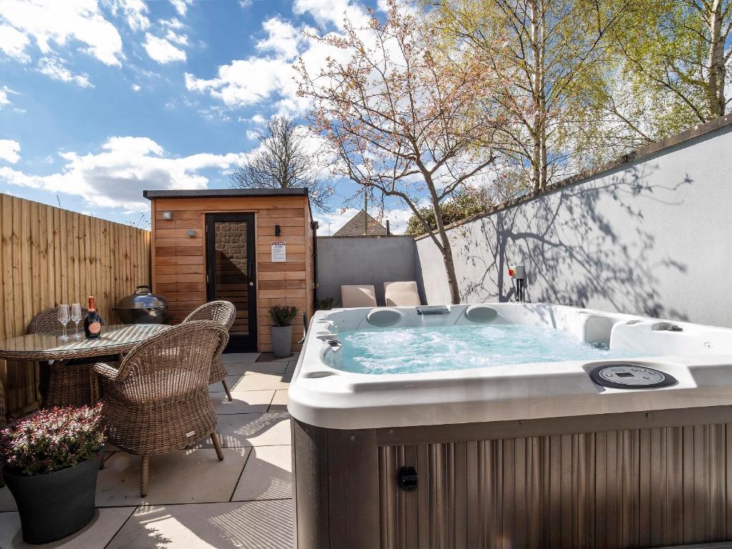 a hot tub on a patio with a table and chairs at The Helmsley Retreat in Helmsley