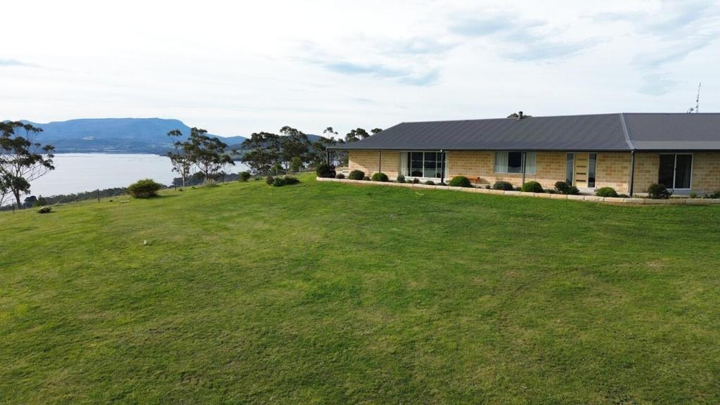 una casa su una collina con un grande campo verde di Bruny Horizon - Where the Country meets the Sea a Killora