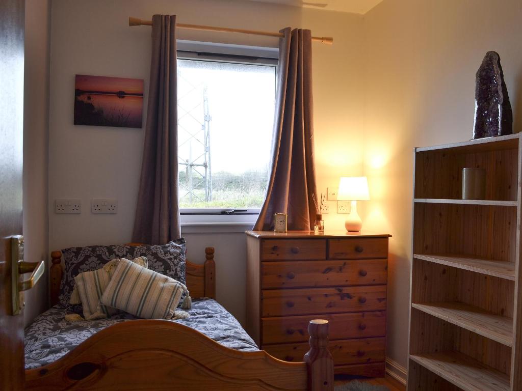 a bedroom with a bed with a dresser and a window at Fair View in Lairg