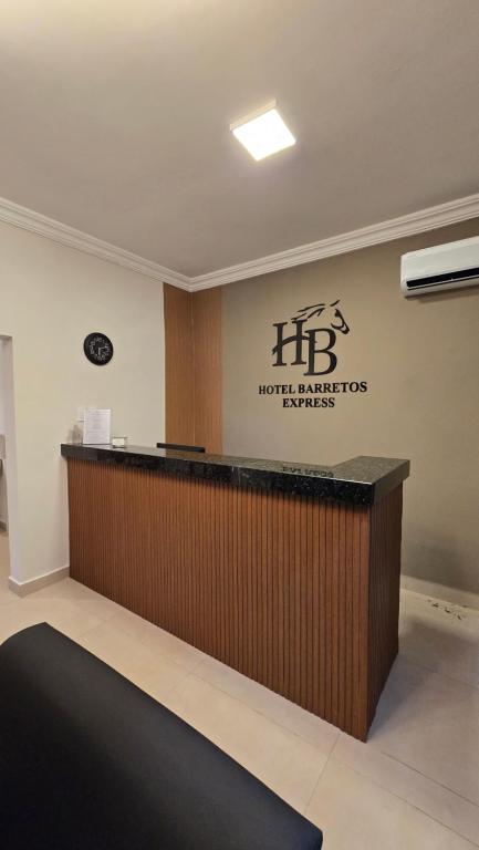 a hotel reception desk with a sign on the wall at Hotel Barretos Express in Barretos