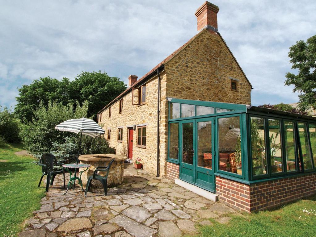 una casa in mattoni con una veranda e un tavolo con un ombrellone di Strawberie Cottage - E2390 a Stoke Abbott
