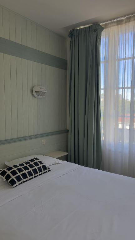 Un dormitorio con una cama blanca y una ventana. en Hôtel le Relais de Vendée, en Les Herbiers