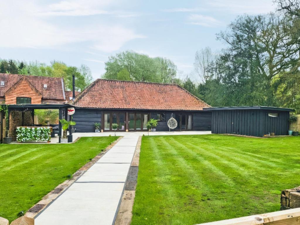 Una casa con un césped verde delante de ella. en The Wilderness Retreat, en Swainsthorpe
