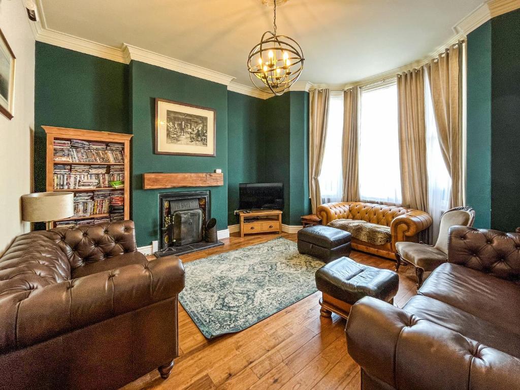 a living room with leather furniture and a fireplace at Olveston in Llandudno