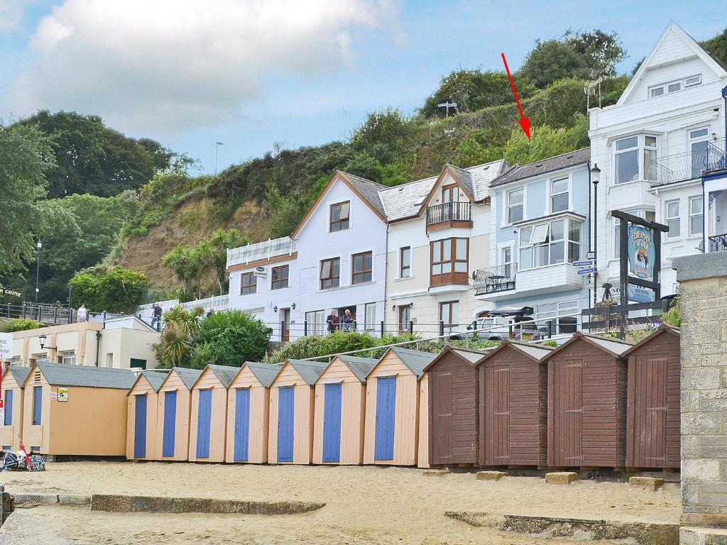 Una hilera de casetas de playa en la arena junto a los edificios. en Chine Bluff, en Shanklin