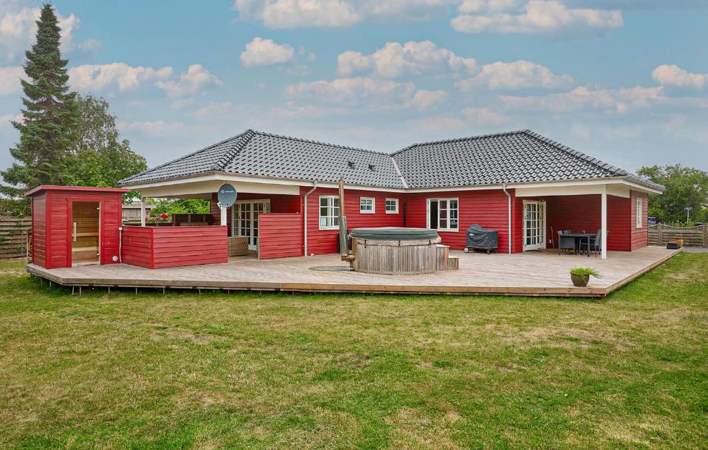 una casa rossa con terrazza e tavolo di Holiday Home Broager With Sauna 261 a Broager