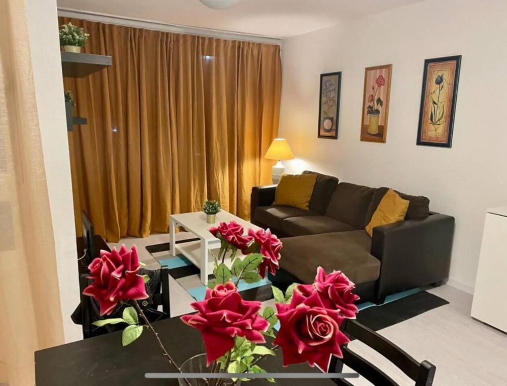 a living room with a couch and a table with red roses at Apartamento 2 Dormitorios Las Americas in Playa de las Americas