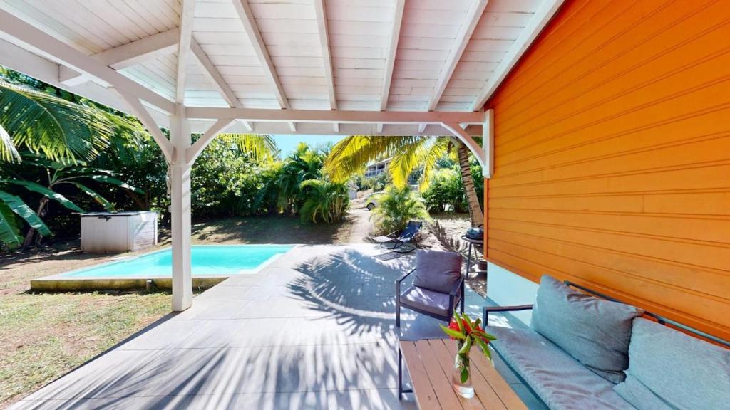 an orange house with a swimming pool and a pergola at LocationTiBalisier pointe sud Martinique in Sainte-Anne