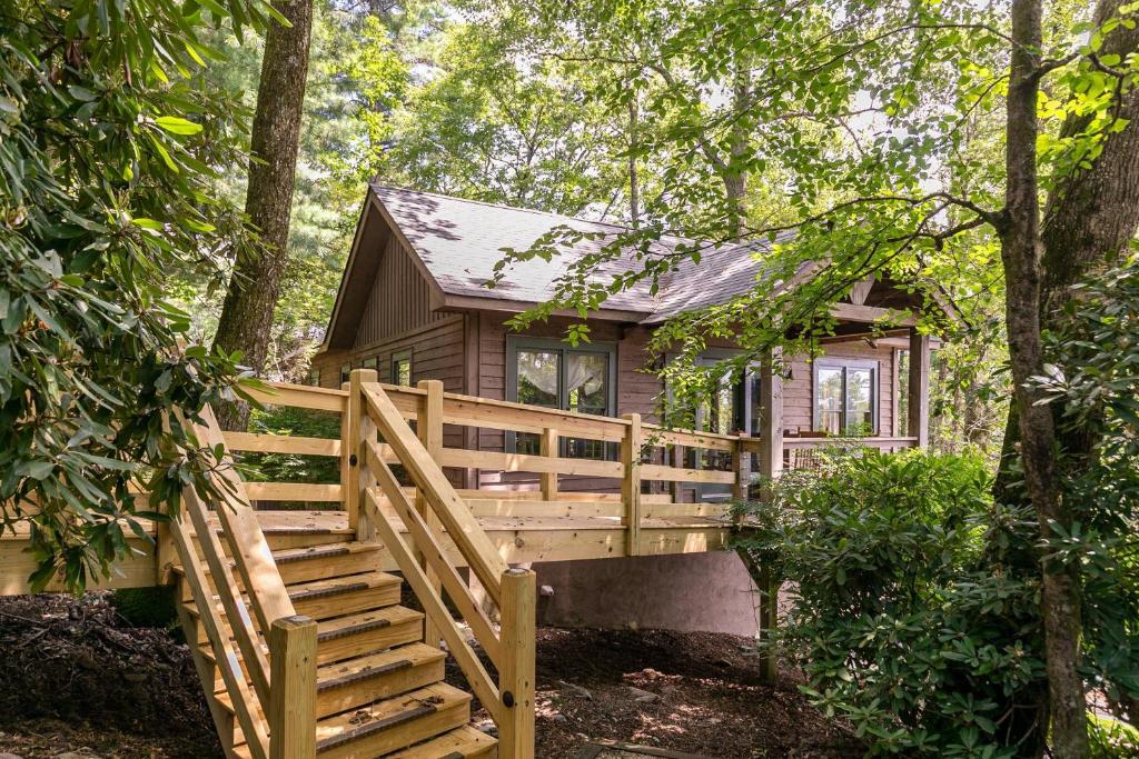 a log cabin in the woods with a wooden fence at Altitudes Attitude in Blowing Rock
