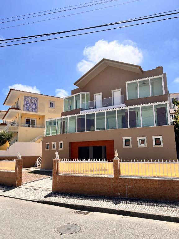 a large house with a yellow fence in front of it at Holiday Villa with Private Pool - Villa Farol in Nazaré