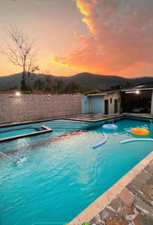 a swimming pool with a sunset in the background at Casa em Bertioga com piscina aquecida Sitio família ROCHA in Bertioga