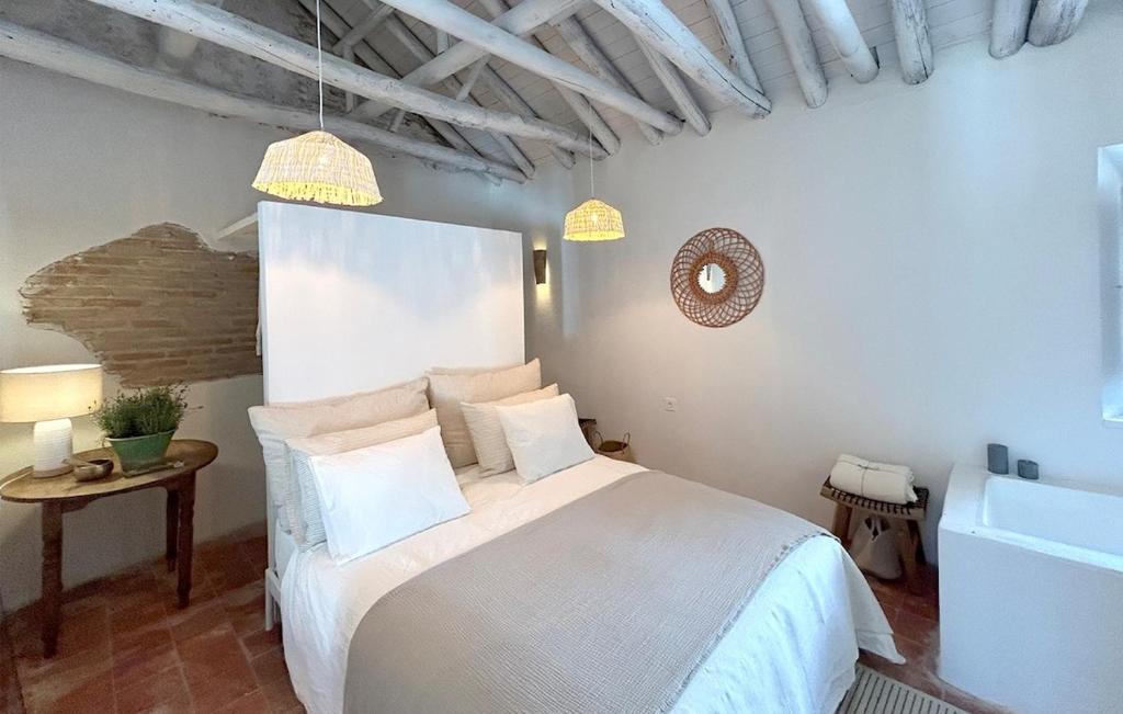 a bedroom with a bed with white sheets and pillows at Casa Alamanda Moclin in Moclín