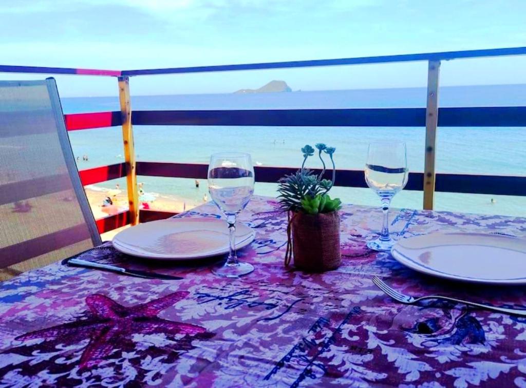 a table with plates and wine glasses on the beach at La Proa Sunrise in La Manga del Mar Menor