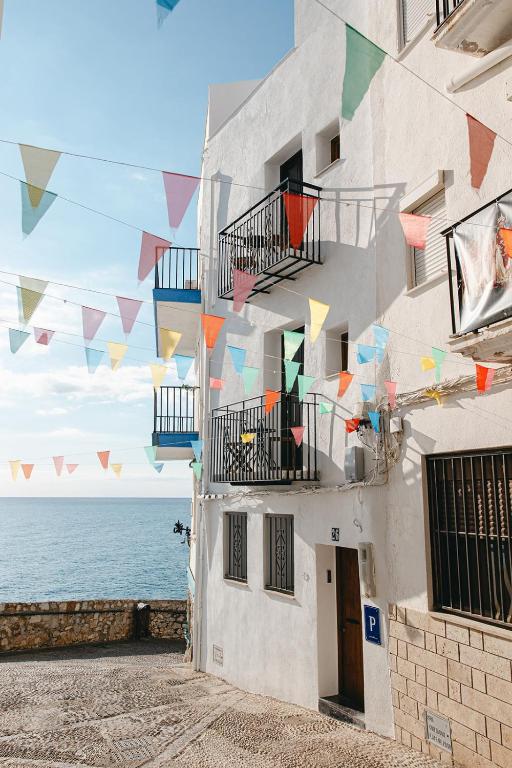 a building with colorful flags hanging from it next to the ocean at Brisaolea - La Parcela in Peniscola