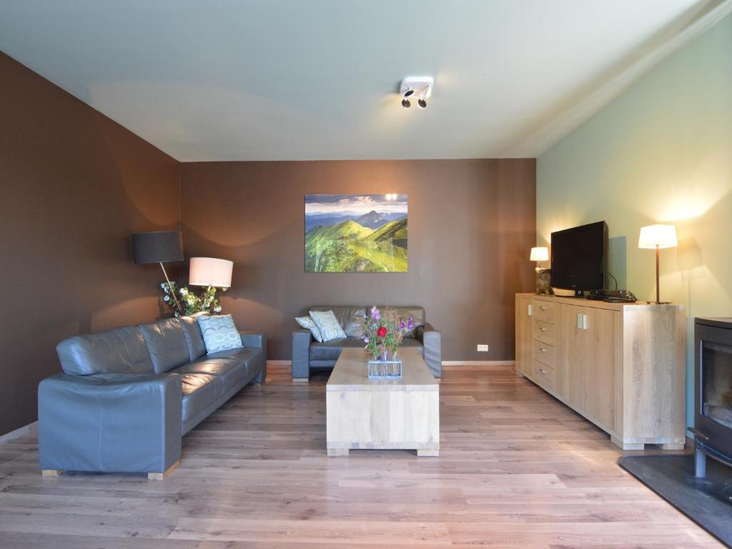 a living room with a couch and a tv at Durbuy Villa with Sauna in Durbuy