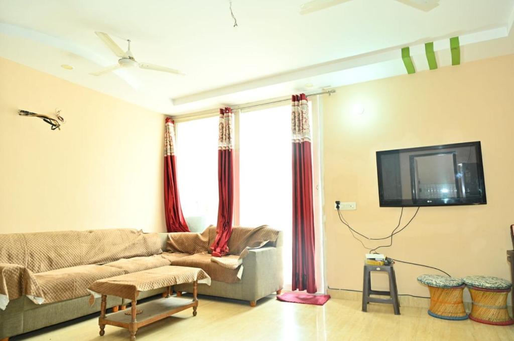 Una sala de estar con un sofá y un televisor. en JD Homestays, en Jaipur