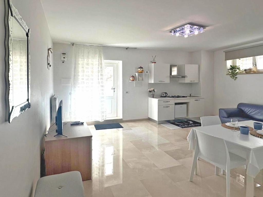 Il comprend un salon blanc avec une table et une cuisine. dans l'établissement AuGuStea-The Nest of Sannicandro, à Sannicandro di Bari