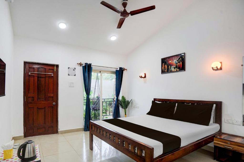 a bedroom with a bed and a ceiling fan at Hotel O fenni and ferns stays in Anjuna