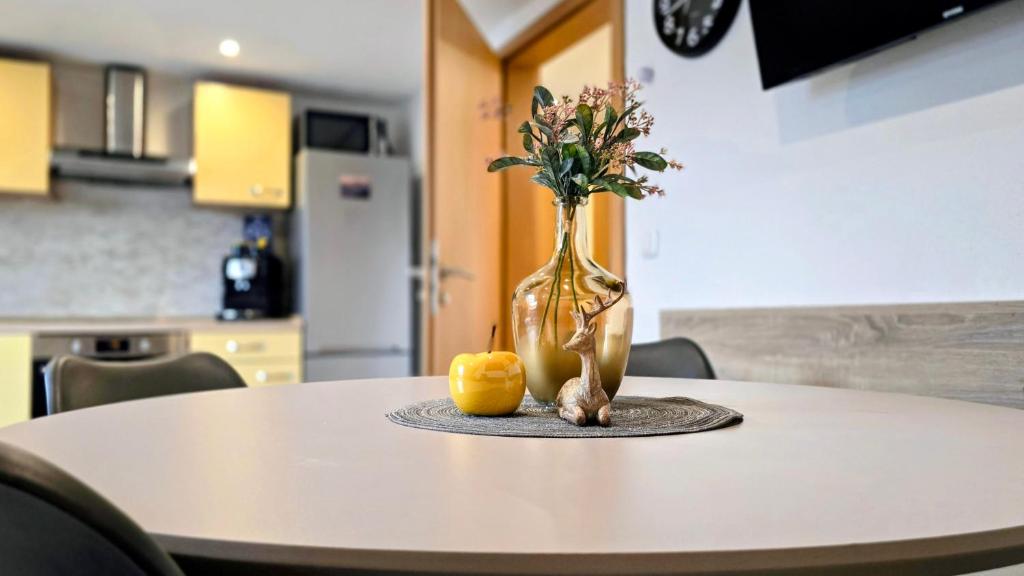 a vase with flowers and two oranges on a table at Falkenstein - Ruhige familienfreundliche 3-Zimmer-Ferienwohnung mit Alpenpanorama in Pfronten Mitte in Pfronten