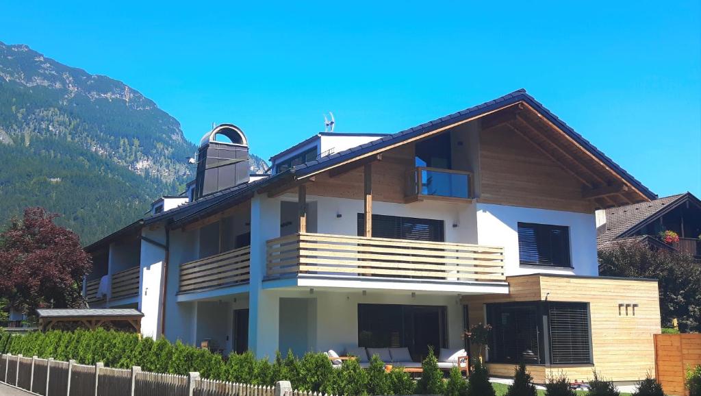 a house with a balcony and mountains in the background at Kandahar Lodge in Garmisch-Partenkirchen