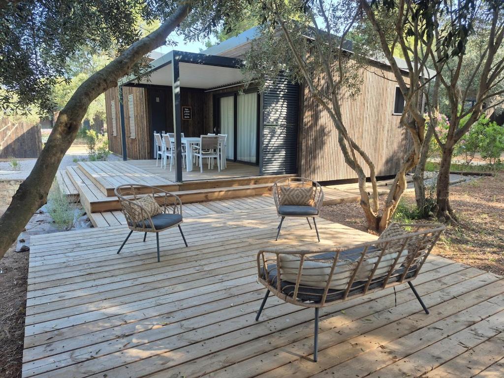 a wooden deck with two chairs and a house at Cap d'Agde Chalet Prestige Calme Piscine Plage in Agde
