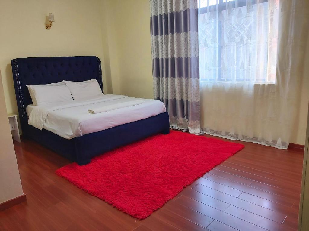 a bed with a red rug next to a window at Mango Court in Nairobi
