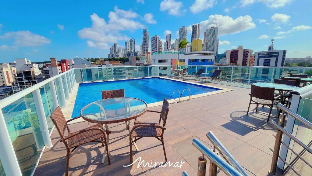 a balcony with a table and chairs and a swimming pool at One Cabo Branco-Poucos Metros da Praia in Tambaú