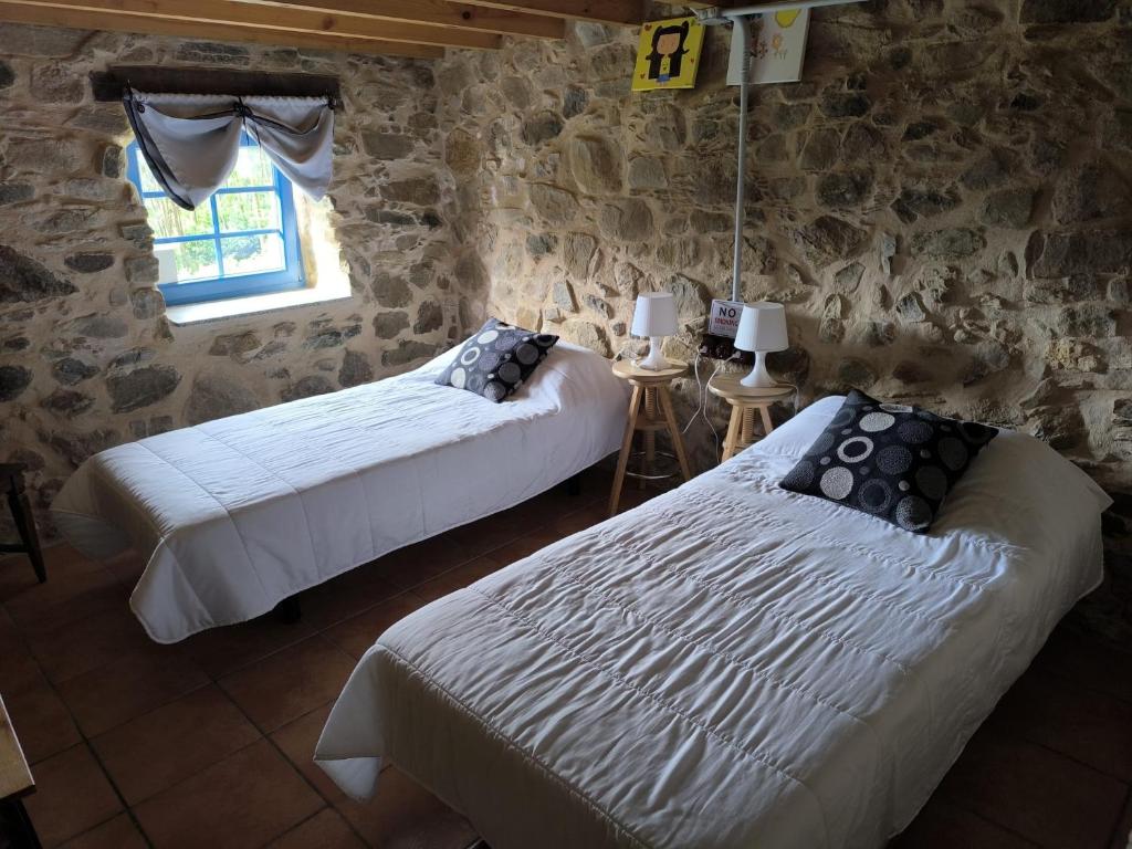 two beds in a room with a stone wall at La Casa de la Fuente 